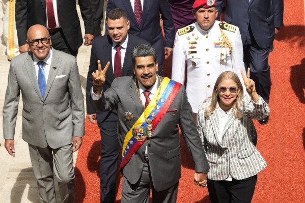 FILE - Venezuelan President Nicolas Maduro and first lady Cilia Flores flash victory signs as they arrive to the National Assembly for the annual presidential address, in Caracas, Venezuela, Jan. 15, 2024. As the July 28 presidential election nears, Venezuelan government keeps arresting opponents allegedly tied to criminal plots. (AP Photo/Ariana Cubillos, File)