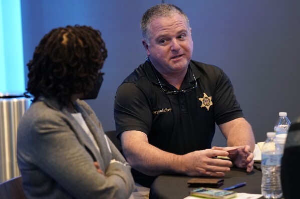 FILE - Rankin County Sheriff Bryan Bailey, right, speaks to an attendee at an employer engagement forum in Jackson, Miss., Nov. 4, 2021. Bailey, the Mississippi sheriff who leads the department where former deputies pleaded guilty to a long list of state and federal charges for the racist torture of two Black men has asked a federal court to dismiss a civil lawsuit against him, Friday, Oct. 6, 2023. (AP Photo/Rogelio V. Solis, File)