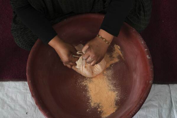 Nevin Qassim, a displaced Palestinian woman, prepares ground lentil dough as a substitute for bread due to a shortage of flour in the Gaza Strip, in Khan Younis, on Sunday, May 11, 2025. (AP Photo/Abdel Karem Hanna)