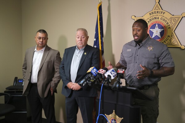 Oklahoma County Sheriff Tommie Johnson III, right, addresses the media in Oklahoma City, Monday, Aug. 28, 2023, alongside Del City Assistant Police Chief Austin Slayten, left, and Del City Police Chief Lloyd Berger, center, during a news conference about the shooting incident at the Del City-Choctaw high school football game on Friday night, Aug. 25. (Doug Hoke/The Oklahoman via AP)