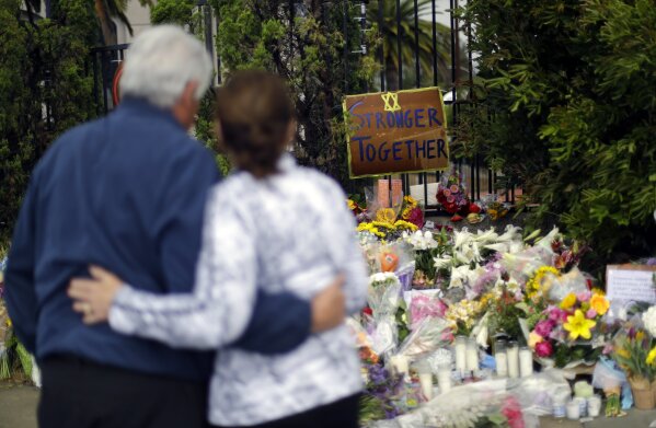 FILE - In this April 29, 2019, file photo, a couple embrace near a growing memorial across the street from the Chabad of Poway synagogue in Poway, Calif. A 19-year-old gunman opened fire as about 100 people were worshipping exactly six months after a mass shooting in a Pittsburgh synagogue, killing one and injuring more. (AP Photo/Greg Bull, File)