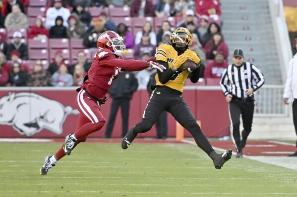 Missouri wide receiver Luther Burden III, front right, makes a catch in front of Arkansas defensive back Lorando Johnson, left, during the first half of an NCAA college football game Friday, Nov. 24, 2023, in Fayetteville, Ark. (AP Photo/Michael Woods)