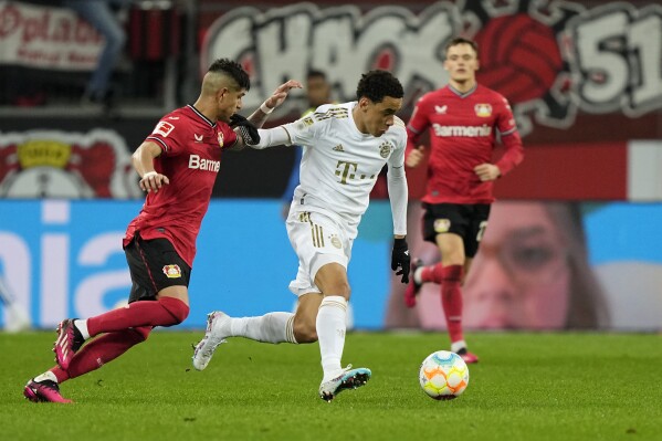 FILE - Bayern's Jamal Musiala, center, and Leverkusen's Piero Hincapie, left, challenge for the ball during the German Bundesliga soccer match between Bayer Leverkusen and Bayern Munich in Leverkusen, Germany, Sunday, March 19, 2023. Bayern Munich hosts Bayer Leverkusen when the Bundesliga returns from the international break with its biggest game of the season so far. Something will need to give on Friday between the only two teams remaining with perfect records. Leverkusen has racked up 11 goals in three wins from three games and leads on goal difference from Bayern. (AP Photo/Martin Meissner, File)