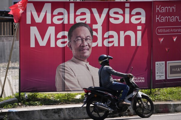 A motorist passes by a giant election poster of Malaysian Prime Minister Anwar Ibrahim ahead of the state election in Kuala Lumpur, Malaysia Wednesday, Aug. 9, 2023. Six of Malaysia’s 13 states are holding elections now because the local governments refused to call for early polls at the same time as general elections in November. They cited the need to prepare for floods during the year-end annual monsoon season. (AP Photo/Vincent Thian)