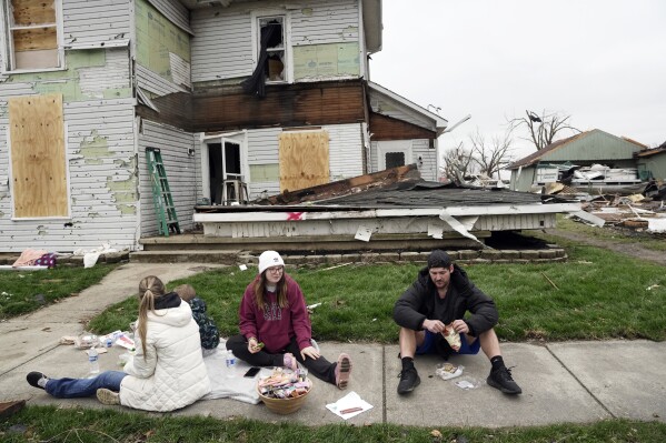 Hunter Vance, right, and Gabrielle Taylor, second from right, eat lunch with others outside a damaged home following a severe storm Friday, March 15, 2024, in Lakeview, Ohio. (AP Photo/Joshua A. Bickel)