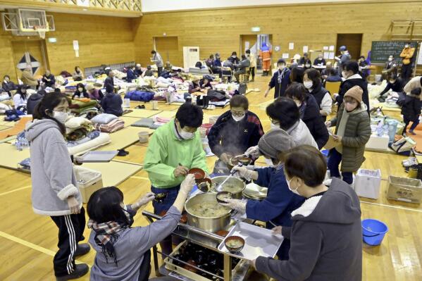 Local residents in the quake-hit area, wait for food distribution at a shelter in Anamizu, Ishikawa prefecture, Sunday, Jan. 7, 2024. Rescue teams worked through snow to deliver supplies to isolated hamlets Monday, a week after a powerful earthquake hit western Japan. (Kyodo News via AP)