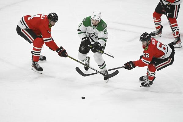 Dallas Stars left wing Jason Robertson (21) moves the puck away from Chicago Blackhawks defenseman Seth Jones (4) and left wing Brett Seney (62) during the second period of an NHL hockey game, Thursday, March 2, 2023, in Chicago. (AP Photo/Matt Marton)