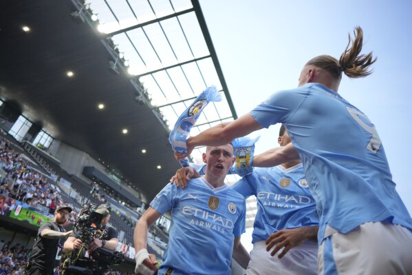 Manchester City's Phil Foden, centre, celebrates with teammates after scoring his side's second goal during the English Premier League soccer match between Fulham and Manchester City at the Craven Cottage Stadium in London, Saturday, May 11, 2024. (AP Photo/Kirsty Wigglesworth)