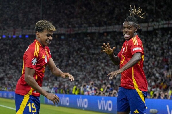 Spain's Nico Williams, right, celebrates with his teammate Lamine Yamal after scoring his side's opening goal during the final match between Spain and England at the Euro 2024 soccer tournament in Berlin, Germany, Sunday, July 14, 2024. (AP Photo/Matthias Schrader)