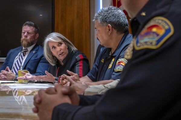 FILE - Gov. Michelle Lujan Grisham, second from left, with Deputy Cabinet Secretary of the Department of Public Safety Benjamin Baker, left, Albuquerque Police Chief Harold Medina, right, speaks during a news conference, Friday, Sept. 8, 2023 in Santa Fe, N.M. Two people were arrested Thursday, Sept. 21, 2022, in connection with a shooting outside an Albuquerque baseball stadium that killed an 11-year-old boy and prompted Grisham to issue a controversial gun ban. (Eddie Moore/The Albuquerque Journal via AP, File)
