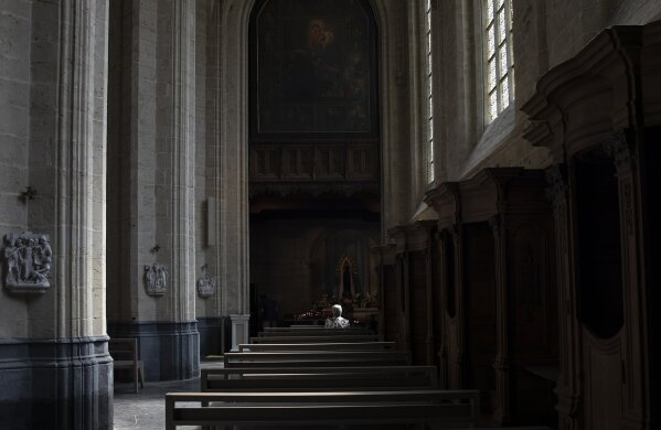 FILE - In this Wednesday, June 24, 2020 file photo, a woman prays at the Saint Martin Basilica in Halle, Belgium during a partial lockdown to prevent the spread of coronavirus, COVID-19. The Belgian government is under pressure to change its restrictive rules on religious services during the coronavirus crisis after Belgium's highest court said the measures impede constitutional conditions on freedom of religion. (AP Photo/Virginia Mayo, File)