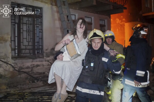 In this photo provided by the Ukrainian Emergency Service, firefighters evacuate a resident from a burning apartment building following Russia's massive air attack in Odesa, Ukraine, Friday, June 20, 2025. (Ukrainian Emergency Service via AP)