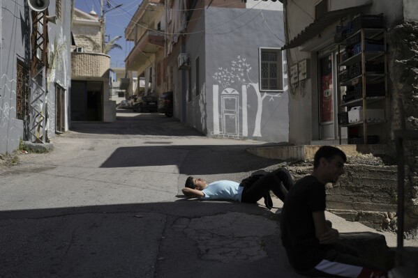 Christian boys rest outside their family home before attending the Washing of the Feet ceremony in Quraye, near the southern port city of Sidon, Lebanon, Thursday, April 17, 2025. (AP Photo/Hassan Ammar)