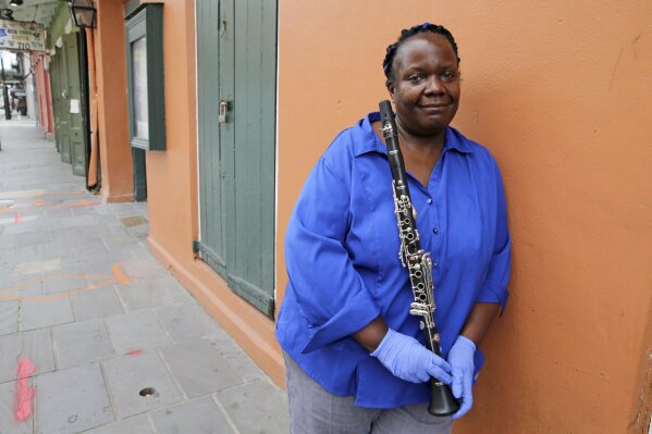 Musician Doreen Ketchens leans against a wall on an empty St. Peter Street in the French Quarter of New Orleans, Wednesday, Aug. 26, 2020. For Ketchens, the coronavirus pandemic is economically much tougher than Katrina. When she isn’t touring the world for clarinet concerts, she’s playing in the French Quarter with her husband (sousaphone) and daughter (drums). After Katrina, she could travel for gigs around the country, but that’s not an option now. A once-full calendar has dwindled to nothing. (AP Photo/Rusty Costanza)