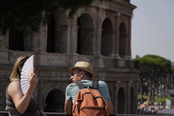 Tourists stops in front of the Colosseum in Rome, Monday, July 17, 2023. Tourist flock to the eternal city while scorching temperatures grip central Italy with Rome at the top of the red alert list as one of the hottest cities in the country. (AP Photo/Gregorio Borgia)