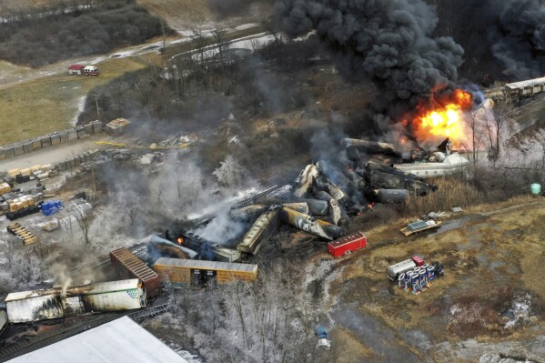 FILE - Debris from a Norfolk Southern freight train lies scattered and burning along the tracks on Feb. 4, 2023, the day after it derailed in East Palestine, Ohio. A federal judge has signed off Tuesday, May 21, 2024, on the $600 million class action settlement over last year's disastrous Norfolk Southern derailment in eastern Ohio, but many people who live near East Palestine are still wondering how much they will end up with out of the deal. (AP Photo/Gene J. Puskar, File)