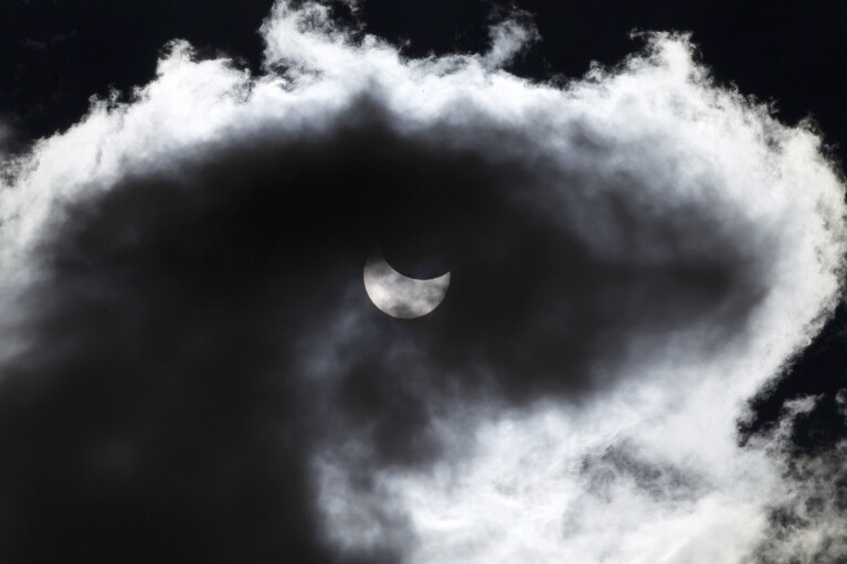 FILE - The moon starts to block the sun during a solar eclipse seen through a cloud, in Skopje, Macedonia, Friday, March 20, 2015, in the last total solar eclipse visible in Europe for over a decade. (AP Photo/Boris Grdanoski, File)
