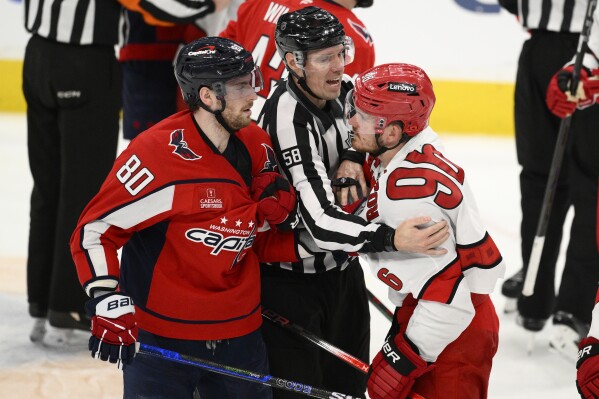 Washington Capitals left wing Pierre-Luc Dubois (80) and Carolina Hurricanes center Jack Roslovic (96) are separated by linesman Ryan Gibbons (58) in the third period of Game 2 of a second-round NHL hockey playoff series Thursday, May 8, 2025, in Washington. (AP Photo/Nick Wass)