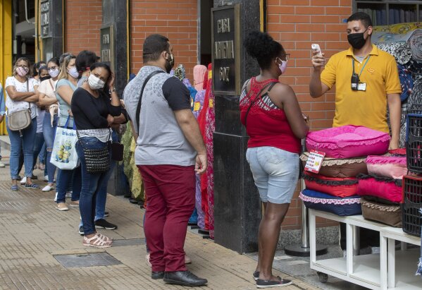 People line up to get their temperatures checked before entering a store in a downtown shopping district of Sao Paulo, Brazil, Wednesday, June 10, 2020. Retail shops reopened on Wednesday in Brazil's biggest city after a two-month coronavirus pandemic shutdown that aimed to contain the spread of the new coronavirus. (AP Photo/Andre Penner)