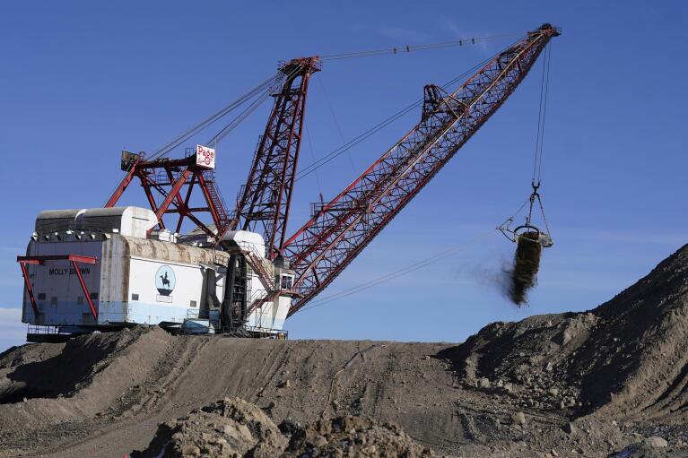 A dragline excavator moves the rock or soil layer that needs to be removed in order to access the coal at Trapper Mining on Thursday, Nov. 18, 2021, in Craig, Colo. The town in northwest Colorado is losing its coal plant, along with the mine that feeds it and residents fear it is the beginning of the end for their community. (AP Photo/Rick Bowmer)