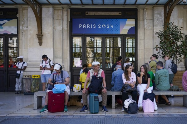 Travelers wait outside the Gare de Bordeaux Saint-Jean at the 2024 Summer Olympics, Friday, July 26, 2024, in Bordeaux, France. Hours away from the grand opening ceremony of the Olympics, high-speed rail traffic was severely disrupted. (ĢӰԺ Photo/Moises Castillo)