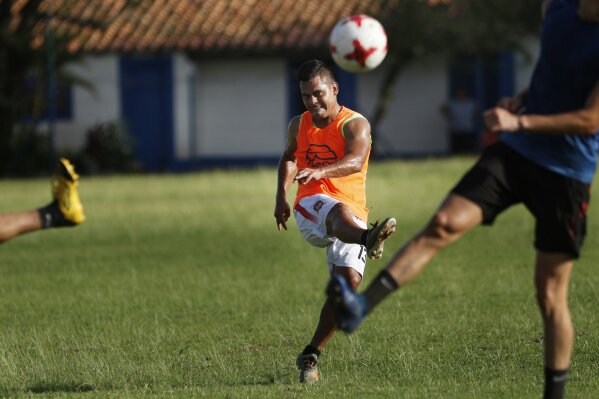 Midfielder Sergio Rojas of Club Sportivo Ameliano of the promotional division, kicks the ball during a training session on his team's pitch, in Asuncion, Paraguay, Friday, Jan. 29, 2021. Because the championship was suspended due to the COVID-19 lockdown, Rojas, 28, a 10-year veteran of the league, now sells eggs and washes cars to survive after not being paid a salary for a year. (AP Photo/Jorge Saenz)