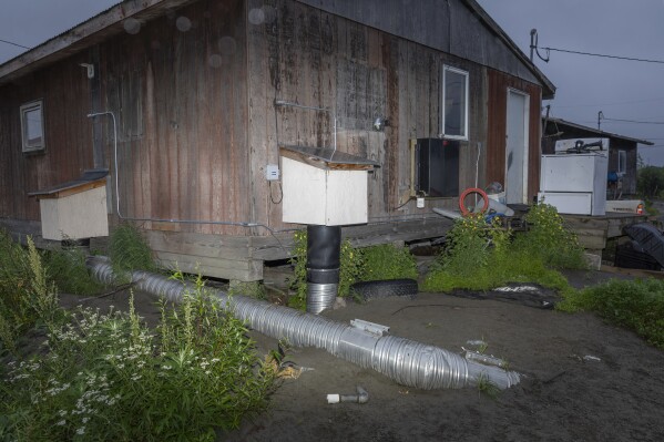 A pipe is visible during evening hours outside the home of Dale Moses, Sunday, Aug. 20, 2023, in Akiachak, Alaska. (AP Photo/Tom Brenner)
