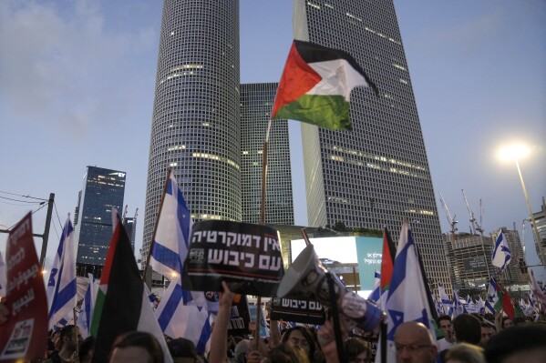 FILE - Demonstrators wave the Israeli and Palestinian flags during a protest against plans by Prime Minister Benjamin Netanyahu's government to overhaul the judicial system, in Tel Aviv, Israel, Saturday, July 22, 2023. Israel is being rocked by a wave of mass protests calling to uphold the country’s democracy. But the cries for democracy lack any clear message of opposition to Israel’s rule over millions of Palestinians, exposing a contradiction that has been coursing through the demonstrations. (AP Photo/Mahmoud Illean, File)