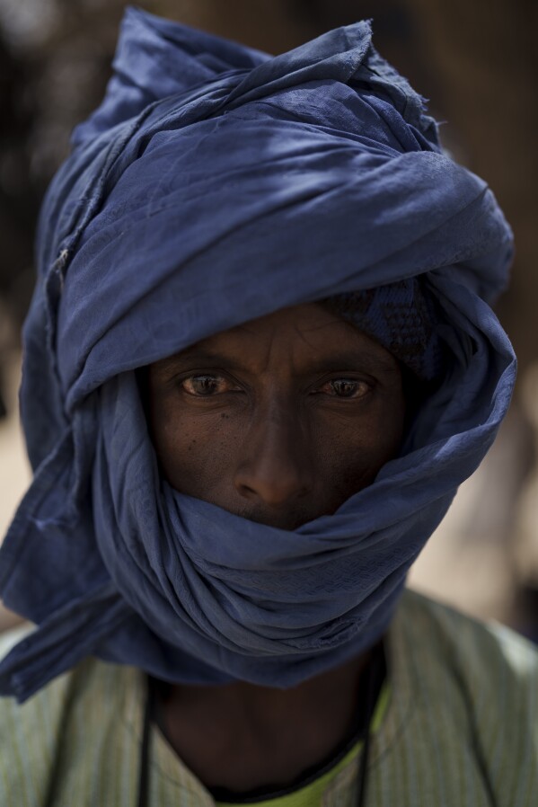 Saydou Kane stands for a portrait at a local market near a water station known as Bem Bem, in the Matam region of Senegal, Wednesday, April. 19, 2023. The 39-year-old herder says one has to know the pleasures and the difficulties in pastoralism. "There is nothing more important than raising livestock. Everything you can imagine is in it," says Kanne. (AP Photo/Leo Correa)