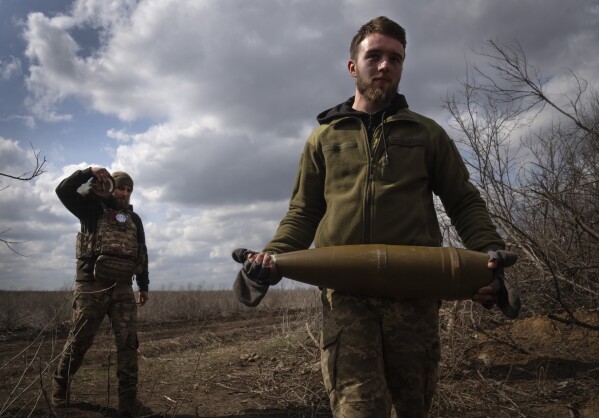 FILE - Ukrainian soldiers carry shells to fire at Russian positions on the front line, near the city of Bakhmut, in Ukraine's Donetsk region, on March 25, 2024. Approval by the U.S. House of a $61 billion package for Ukraine puts the country a step closer to getting an infusion of new firepower. But the clock is ticking. Russia is using all its might to achieve its most significant gains since the invasion by a May 9 deadline. (AP Photo/Efrem Lukatsky, File)