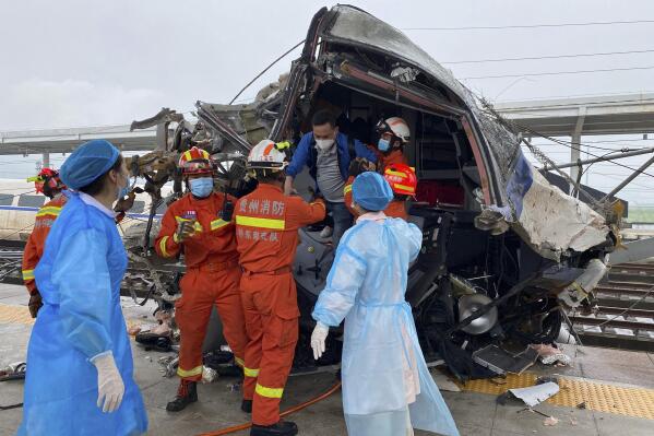 In this photo released by China's Xinhua News Agency, emergency personnel help a passenger off a damaged train car after it derailed in Rongjiang County in southwestern China's Guizhou Province, Saturday, June 4, 2022. The driver of a high-speed train in southern China was killed and several people were injured when two cars derailed early Saturday after hitting a mudslide, state broadcaster CCTV reported. (Xinhua via AP)