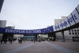 People walk under a banner advertising the European elections outside the European Parliament in Brussels, Jan. 24, 2024. (AP Photo/Virginia Mayo)