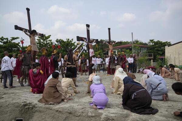 Wilfredo Salvador, center, and two actors stay on crosses during a reenactment of Jesus Christ's sufferings as part of Good Friday rituals April 7, 2023 in the village of San Pedro, Cutud, Pampanga province, northern Philippines. The real-life crucifixions, a gory Good Friday tradition that is rejected by the Catholic church, resumes in this farming village after a three-year pause due to the coronavirus pandemic.(AP Photo/Aaron Favila)