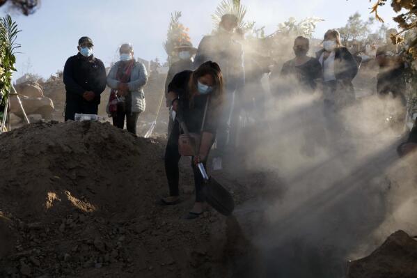 FILE - In this June 25, 2021, file photo, a family member shovels dirt into the grave of Giro Quispe who died from complications related to the coronavirus, at El Cebollar cemetery, in Arequipa, Peru. COVID-19 has spread misery and despair and exposed stark global inequities on its way to 4 million dead worldwide. (AP Photo/Guadalupe Pardo, File)