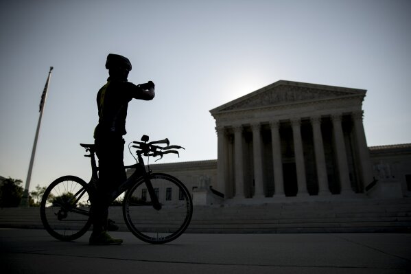 A man on a bicycle stops to take a photograph outside the Supreme Court, Wednesday, July 8, 2020, in Washington. (AP Photo/Andrew Harnik)
