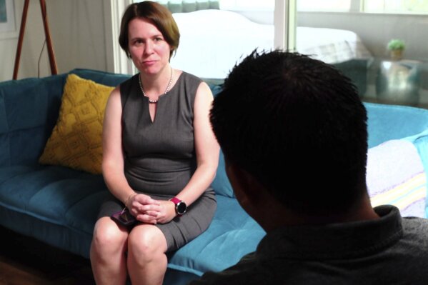 In this Aug. 7, 2019 image made from video, attorney Michelle Lapointe speaks with her client, a Guatemalan immigrant, in Santa Ana, Calif. The father is preparing to sue the federal government, alleging his 8-year-old boy was sexually molested in a foster care home funded by the U.S. Health and Human Services agency. He says he is still struggling to soothe his son’s lasting nightmares, and that the 3rd grader, once talkative and outgoing, is now withdrawn and frequently says he wants to leave this world. (AP Photo/Krysta Fauria)