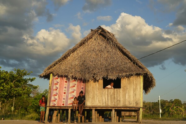 Members of an Indigenous Wari' family sit in their house in the community of Guajara-Mirim, Rondonia state, Brazil, Thursday, July 13, 2023. (AP Photo/Andre Penner)