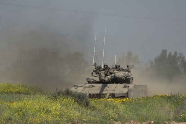 Israeli soldiers move on the top of a tank near the Israeli-Gaza border, as seen from southern Israel, Thursday, March 21, 2024. (AP Photo/Ohad Zwigenberg)