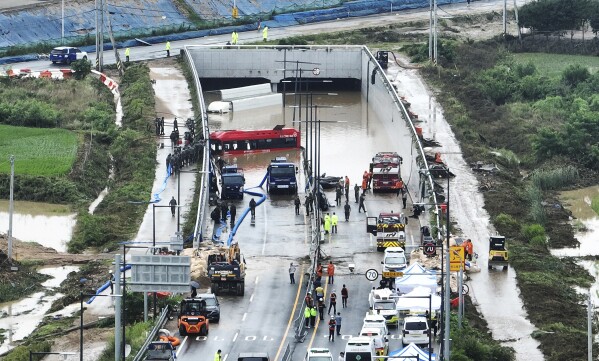 Rescuers work to search for survivors along a road submerged by floodwaters leading to an underground tunnel in Cheongju, South Korea, Sunday, July 16, 2023. (Kim Ju-hyung/Yonhap via AP)