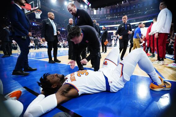 A trainer checks on New York Knicks' Julius Randle (30) after he was hurt during the first half of Game 5 of the team's NBA basketball Eastern Conference playoff semifinal against the Miami Heat on Wednesday, May 10, 2023, in New York. The Knicks won 112-103. (AP Photo/Frank Franklin II)