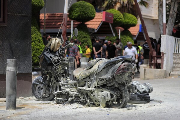A charred motorcycle is seen after an Israeli strike outside Salah Ghandour Hospital, background, in Bint Jbeil town, south Lebanon, Monday, May 27, 2024. An Israeli strike targeting a motorcycle in the town of Bint Jbeil in south Lebanon Monday hit next to a hospital entrance, killing at least one person and injuring several civilians who were gathered outside the facility, local health officials said. (AP Photo/Mohammad Zaatari)