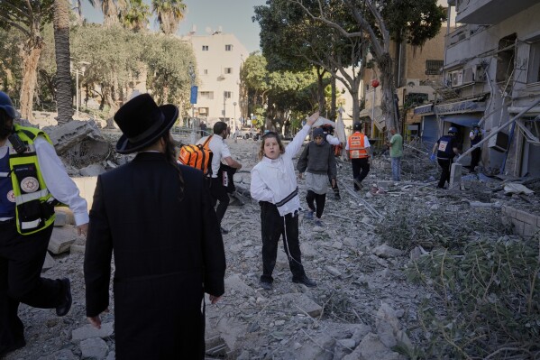Rescue workers and residents react at the site where a missile launched from Iran struck in Haifa, Israel, Sunday, June 22, 2025. (AP Photo/Baz Ratner)