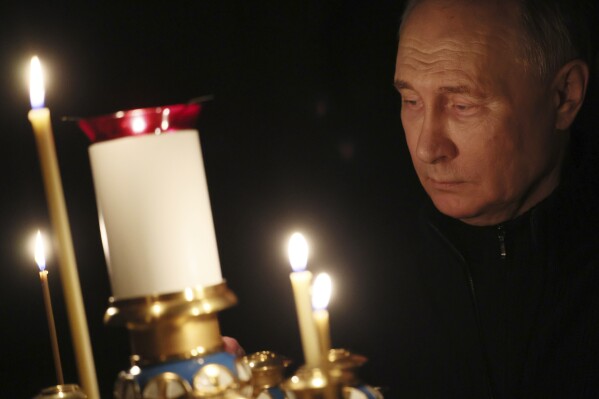 Russian President Vladimir Putin lights a candle to commemorate the victims of an attack on the Crocus City Hall concert venue, on the day of national mourning, in Russia, Sunday, March 24, 2024. (Mikhail Metzel, Sputnik, Kremlin Pool Photo via AP)