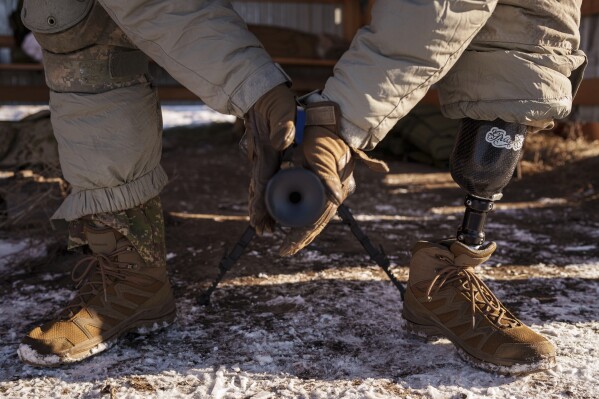 Serhii Pozniak, a commander with a Ukrainian sniper unit who lost a leg after stepping on a mine, mounts a suppressor on his rifle during military training near Kyiv, Ukraine, on Feb. 17, 2025. (AP Photo/Evgeniy Maloletka)
