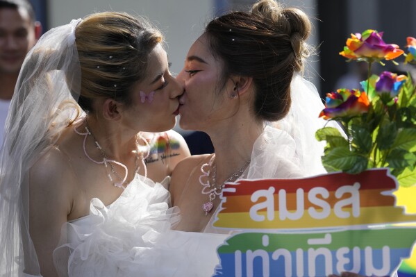FILE - Women kiss while holding a poster to support marriage equality, during a Pride Parade in Bangkok, Thailand, on June 4, 2023. Thailand’s Cabinet on Tuesday, Nov. 21, approved an amendment to its civil code to allow same-sex marriage, with an expectation for the draft to be submitted to Parliament next month. (AP Photo/Sakchai Lalit, File)
