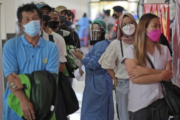 A medical worker in protective gear checks the paperwork of people getting the Sinovac COVID-19 vaccine during a mass vaccination in Depok on the outskirts of Jakarta, Indonesia, Friday, June 25, 2021. The world's fourth most populous country, has seen COVID-19 infections surge in recent weeks, putting pressure on hospitals, including in the capital city, where most of hospital beds are full, and has added urgency to the government's plan to inoculate 1 million people each day by next month. (AP Photo/Dita Alangkara)