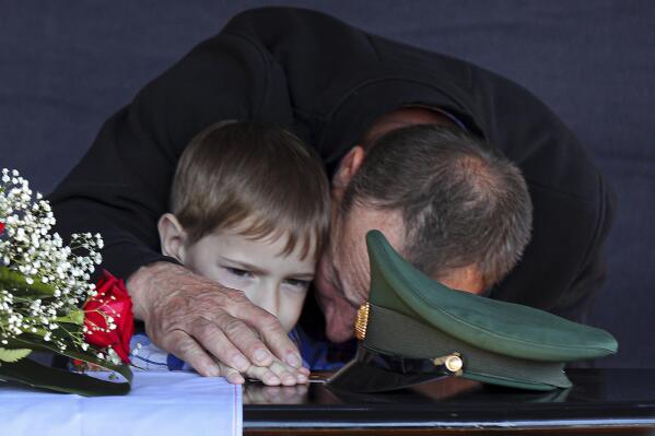 FILE – The father and son of Russian army Sgt. Daniil Dumenko, 35, who was killed in Ukraine, mourn his death at a ceremony in Volzhsky, outside Volgograd, Russia, on May 26, 2022. Some experts warn that the war, which already has killed tens of thousands on both sides and reduced entire cities to ruins, could drag on for years. (AP Photo, File)