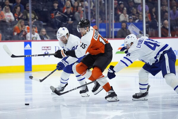 Philadelphia Flyers' Denis Gurianov, center, chases after the puck with Toronto Maple Leafs' Morgan Rielly, left, and Ilya Lyubushkin during the second period of an NHL hockey game, Thursday, March 14, 2024, in Philadelphia. (AP Photo/Matt Slocum)