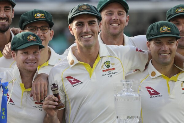 FILE - Australia's captain Pat Cummins, center, holds the Ashes Urn as Australia retain the trophy on day five of the fifth Ashes Test match between England and Australia, at The Oval cricket ground in London, on July 31, 2023. Cummins, Steve Smith, Glenn Maxwell and Mitchell Starc may not be fit to play before the start of the Cricket World Cup in India next month, but all were named Wednesday, Sept. 6, 2023 in Australia's provisional squad for the tournament. (AP Photo/Kirsty Wigglesworth, File)