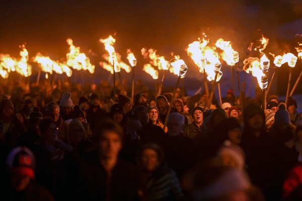 People carry torches en route to the beetle before setting it on fire during the 11th annual Burning Beetle event on Saturday, Jan. 20, 2024, at Pageant Park in Custer, S.D. The event was created in response to the Mountain Pine Beetle infestation a few years ago and continues to raise awareness of the impact of the beetles. (Matt Gade/Rapid City Journal via AP)
